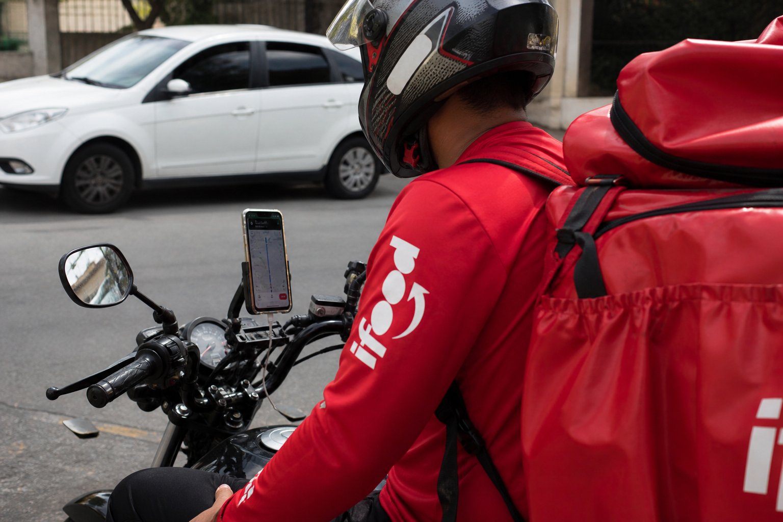 Entregador iFood em motocicleta com celular acoplado — bloqueio de conta em plataformas digitais